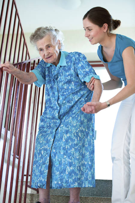 A caregiver with an elderly woman on the stairs