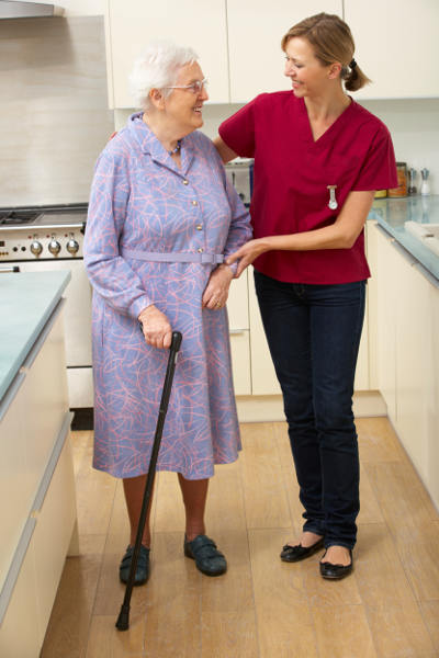 woman in kitchen with cane and caregiver
